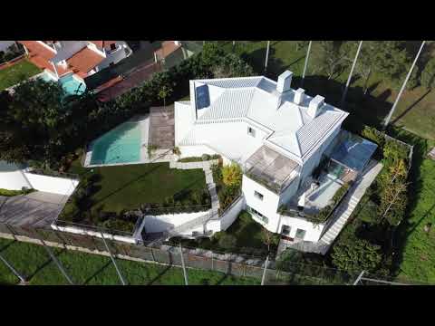 Aerial view of a modern white house with pool.
