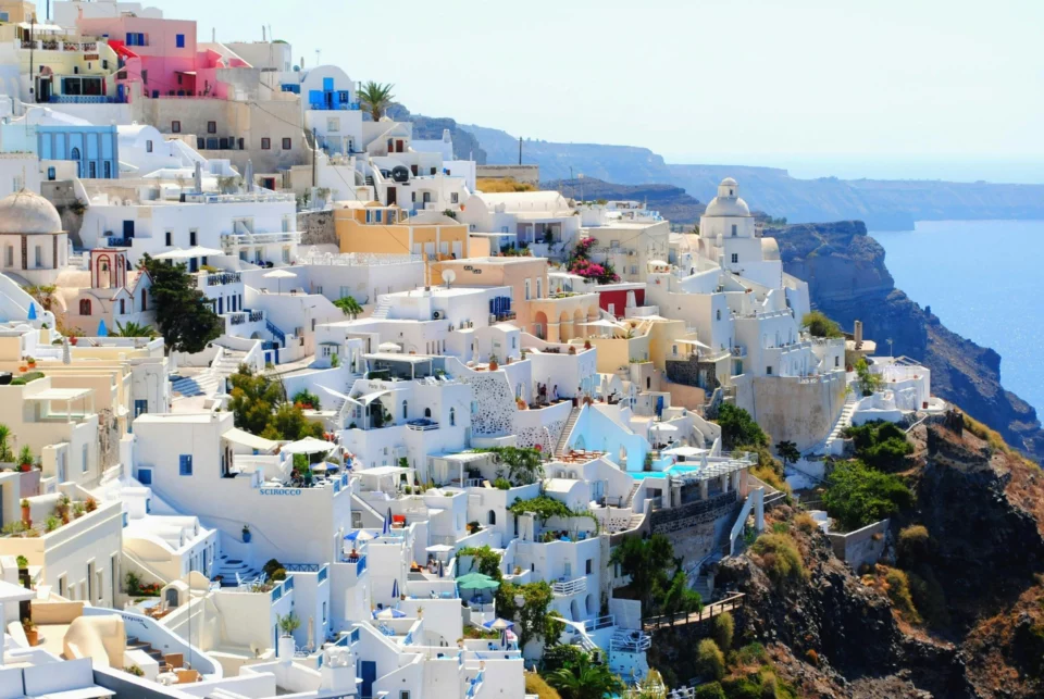 Iconic view of whitewashed buildings with colorful accents on the cliffs of Santorini, Greece, overlooking the Aegean Sea.