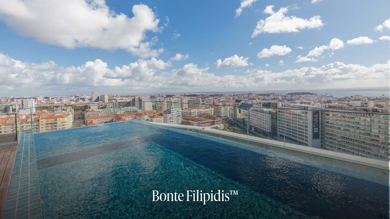 Infinity pool overlooking city skyline and clouds.
