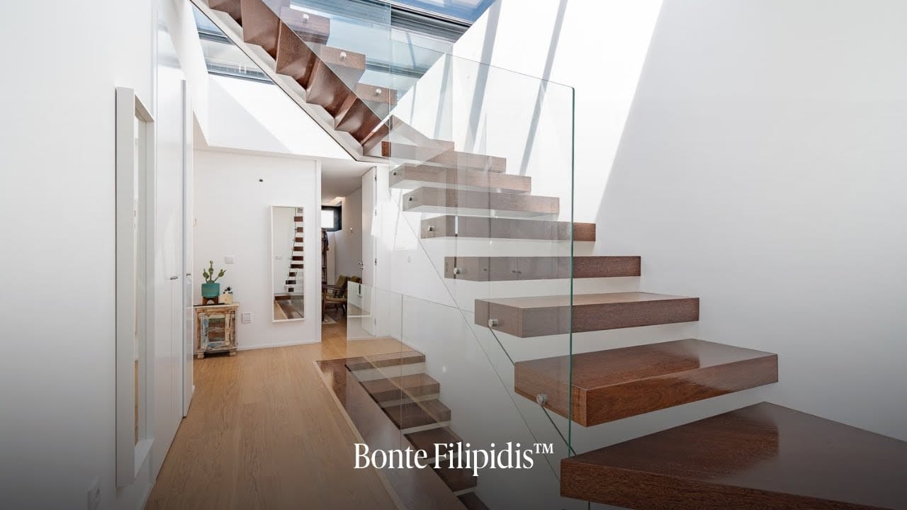 Modern staircase with glass railings and wooden steps.