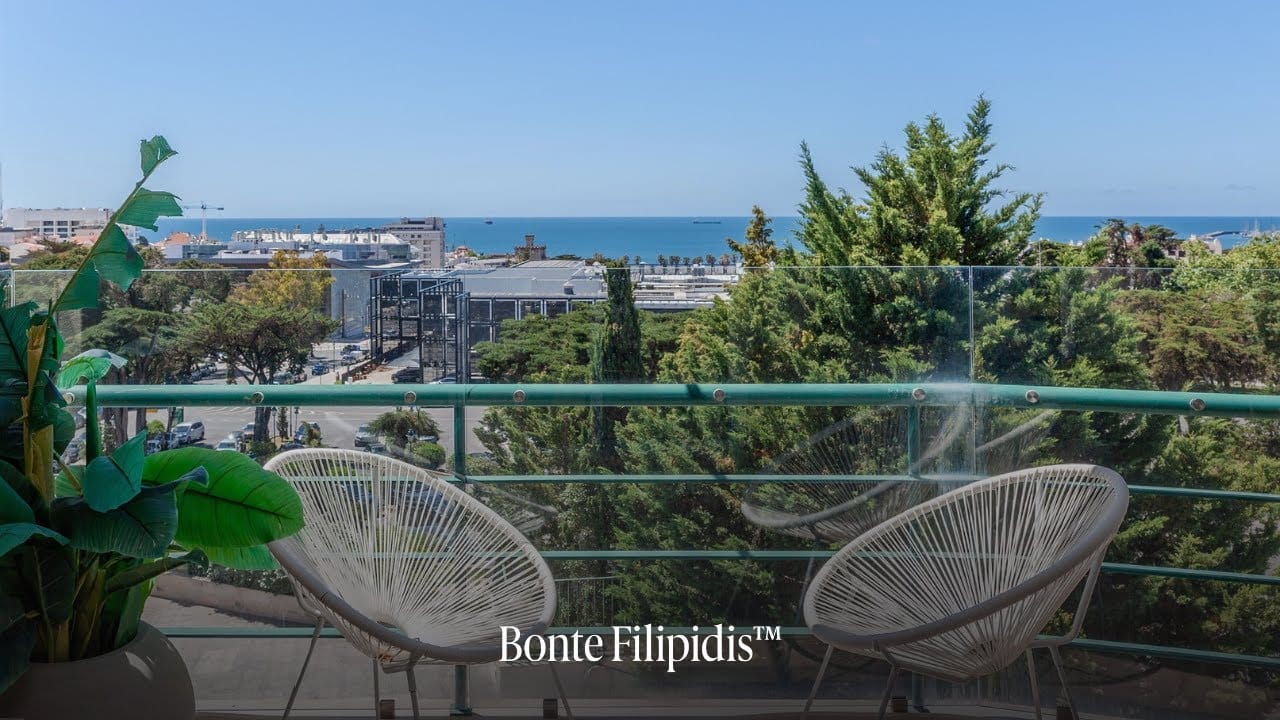 Balcony view with ocean and greenery.